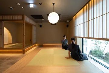 畳の共用ラウンジ。丸いペンダントライトと障子